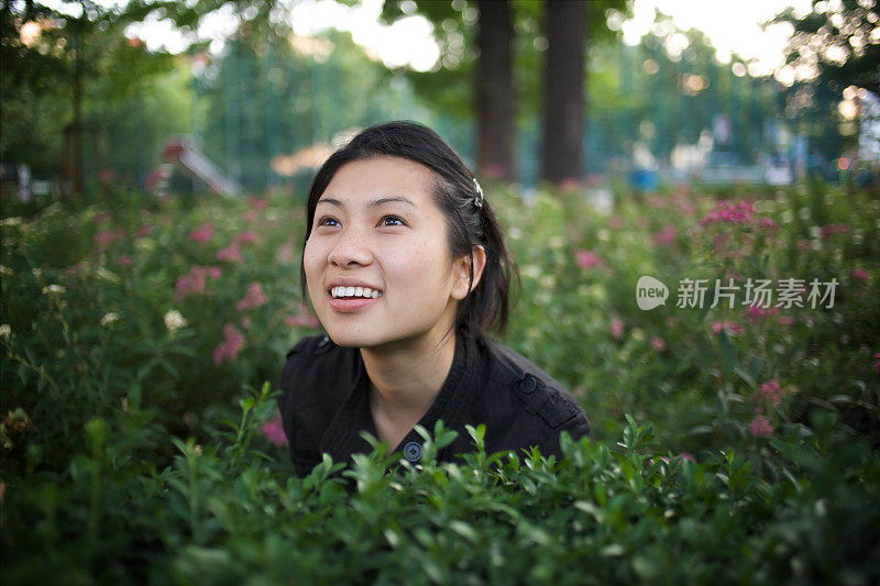 笑着坐在花丛中的亚洲年轻女子