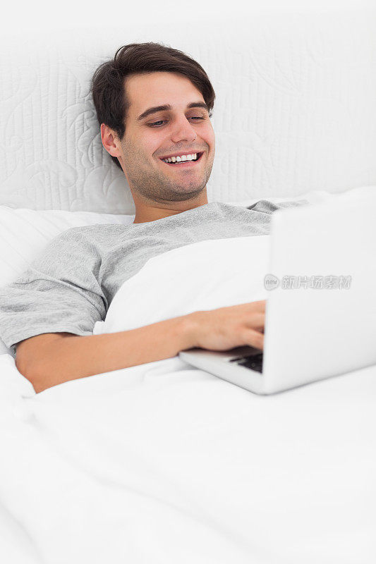 一个在床上用笔记本电脑的男人