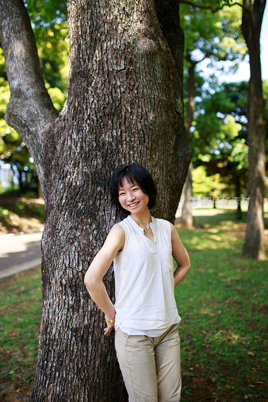 站在树旁微笑的日本妇女