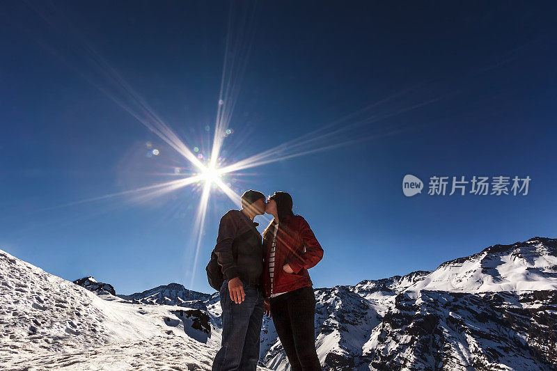 一对情侣在明亮的太阳下亲吻雪山