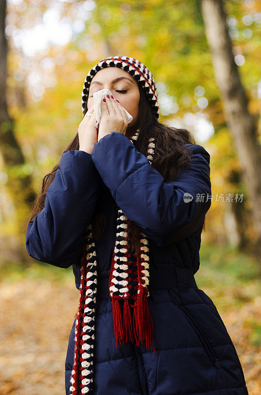 女人在秋天用手帕打喷嚏