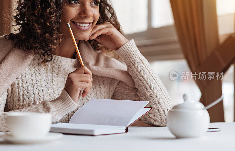 一个积极的非裔美国女人在咖啡馆做笔记