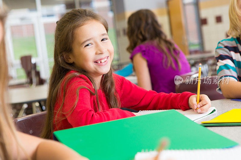 年轻的小学生在学校做作业时微笑