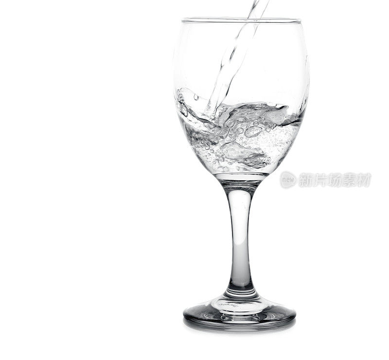 水倒入一个透明的葡萄酒杯，白色的背景。
