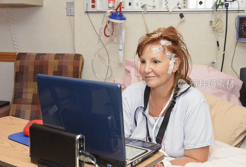在医院病床上拿着笔记本电脑的女人