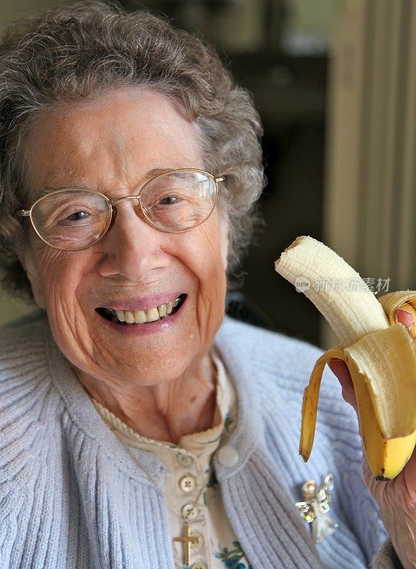 一个戴眼镜的老妇人在吃香蕉