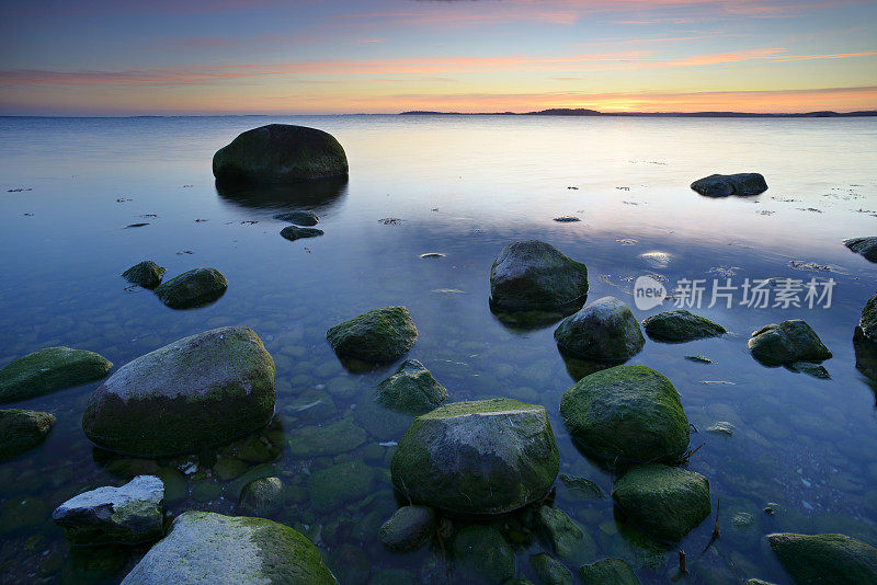 日落的海景与苔藓覆盖的巨石，鲁根岛，德国