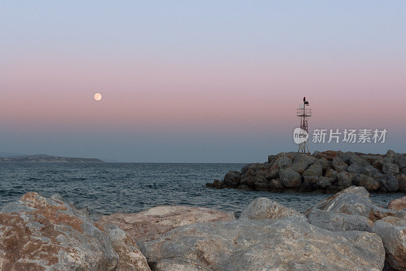 夏日希腊岛港口日落时的满月