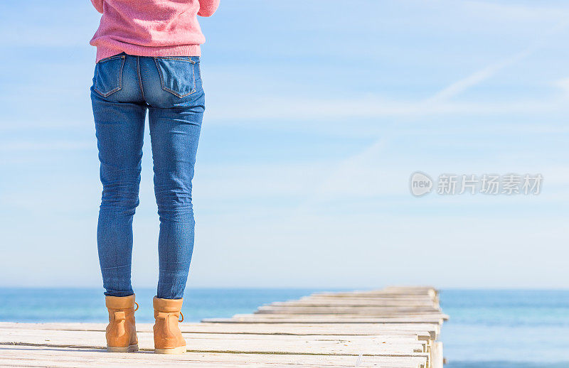 女人的腿站在海上的码头上