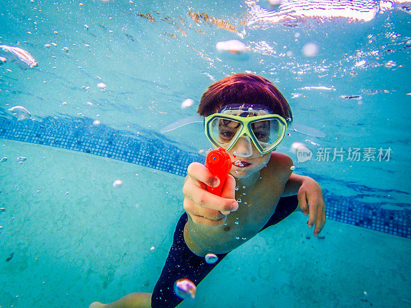 游泳男孩戴着面具和水枪