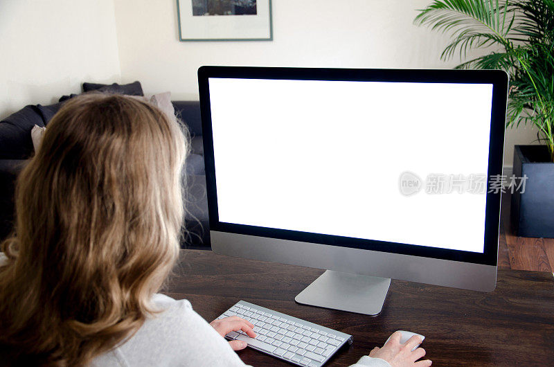 一个女人在电脑前工作，屏幕是空白的