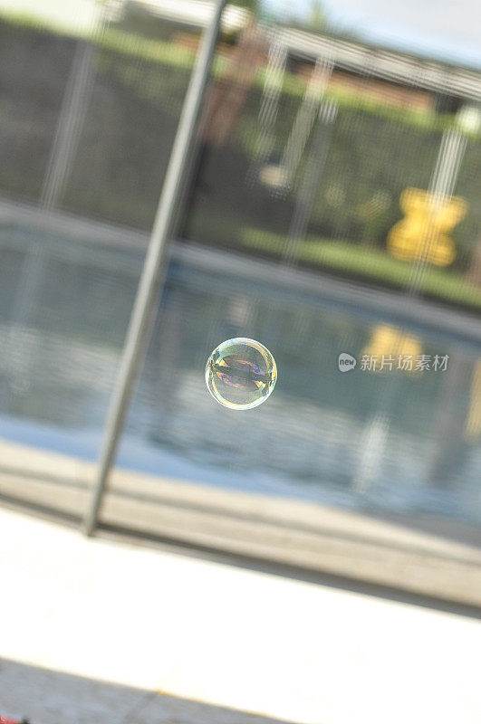 泡泡漂浮在后院的游泳池和秋千上。