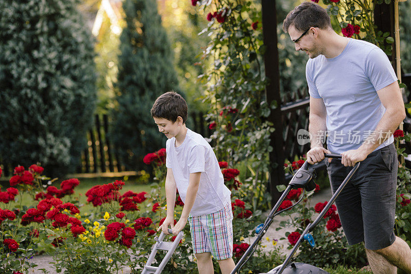 快乐的父亲和儿子一起修剪后院。