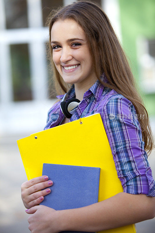 年轻的女学生站在学校前面