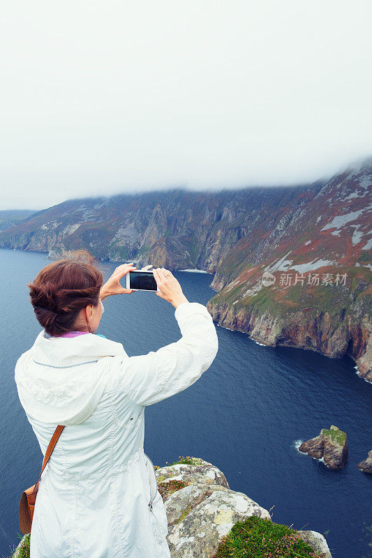 一名女子正在拍摄岩壁联盟悬崖的照片