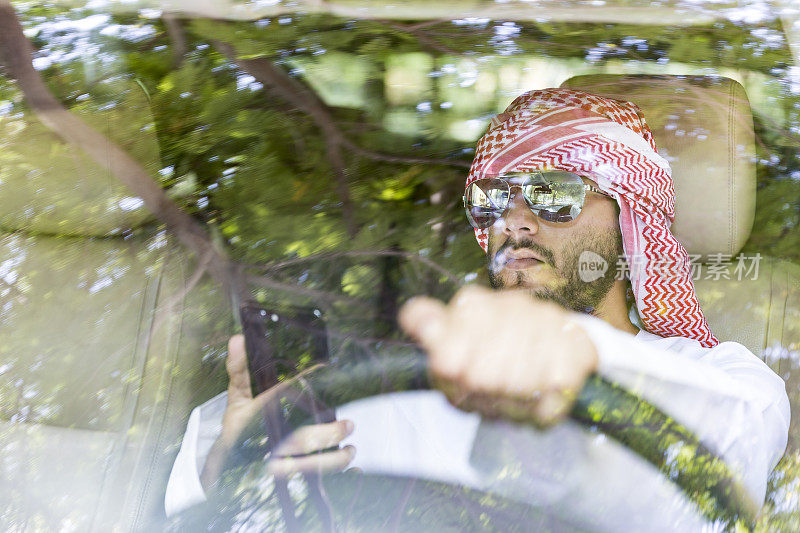 年轻的阿拉伯人一边开着豪华车一边发短信