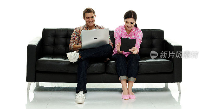 微笑的情侣使用平板电脑和笔记本电脑