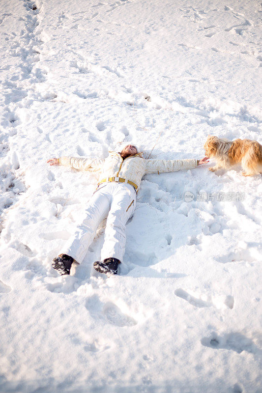 一个女人带着狗在雪地里走在村里的街道上