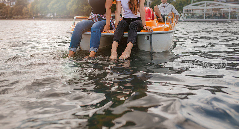脚踏船上的两个年轻女人，脚浸在水里
