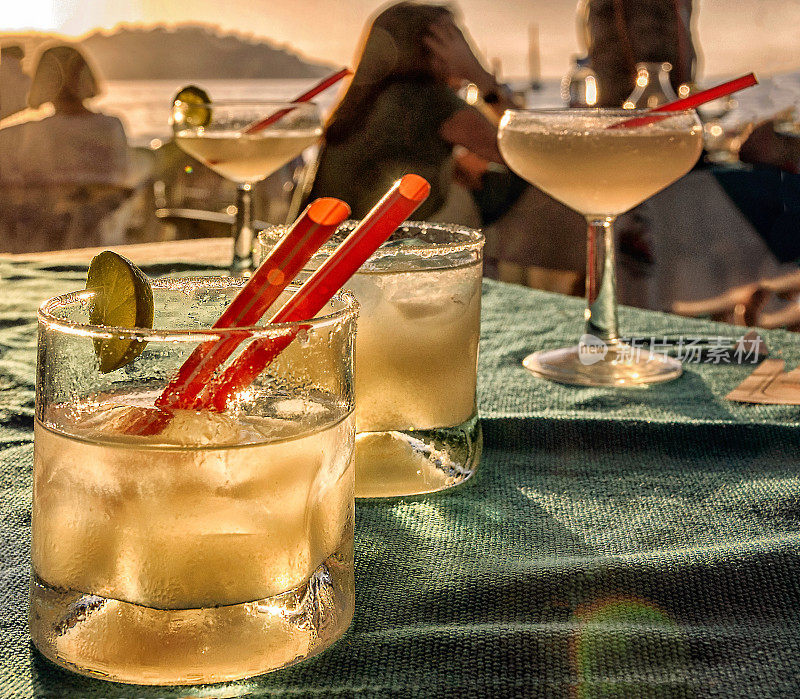 海滩酒吧的桌子，玛格丽塔鸡尾酒饮料和海滩日落的背景