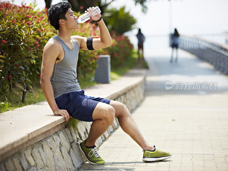 年轻的亚洲成年人在运动中喝水