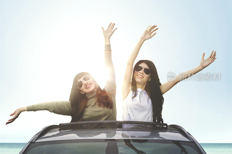 快乐的女人在汽车天窗上享受自由