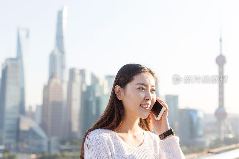 年轻美丽的亚洲女人在现代城市玩手机