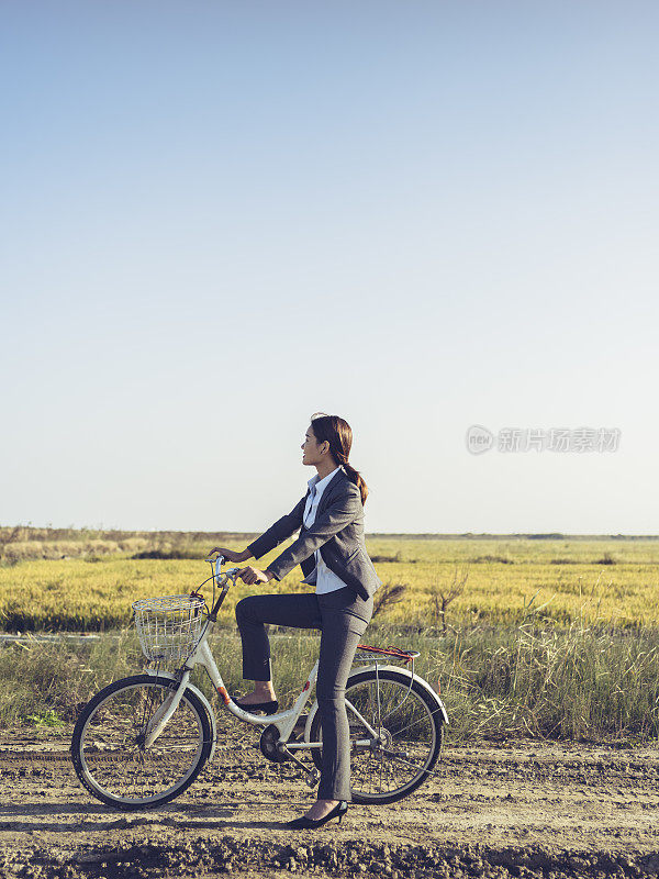 一个年轻的女商人坐在乡下的bicyale上的肖像