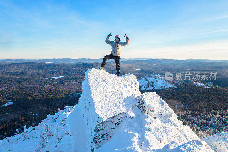 那位登山者爬上了山顶，一个徒步旅行者站在岩石的顶峰庆祝成功。