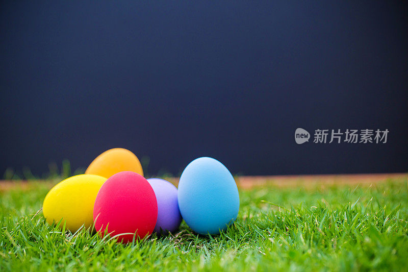 把复活节彩蛋放在以黑板为背景的草地上。复活节的象征。自然背景