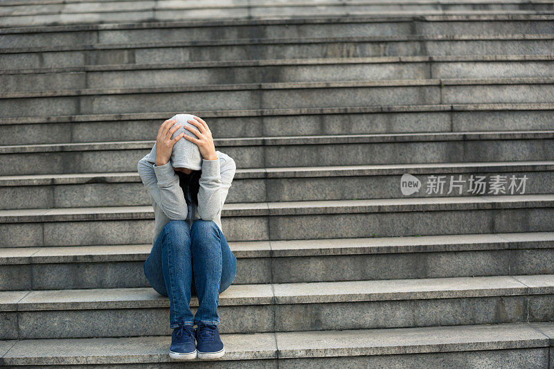 一个女人独自坐在城市的楼梯上