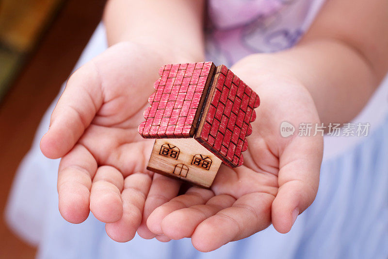 小女孩手里拿着一个小玩具房子