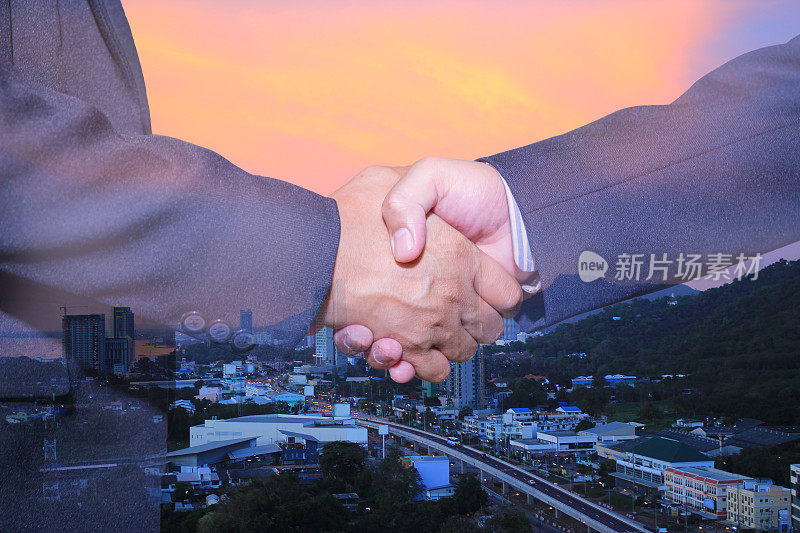 握手和城市双重曝光。握手和商务人士的概念。两名男子握手孤立的城市景观背景。