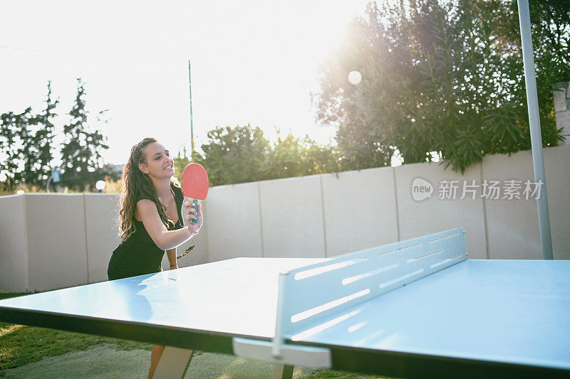 可爱的女孩在她的前院打乒乓球