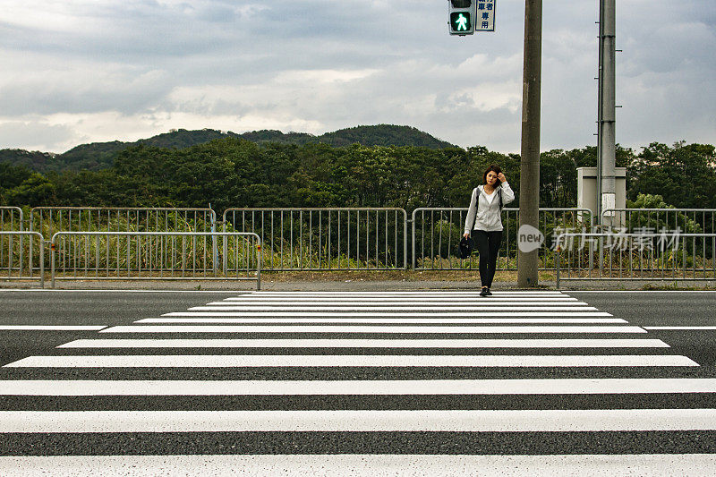 一名年轻女子正在过马路上的人行道