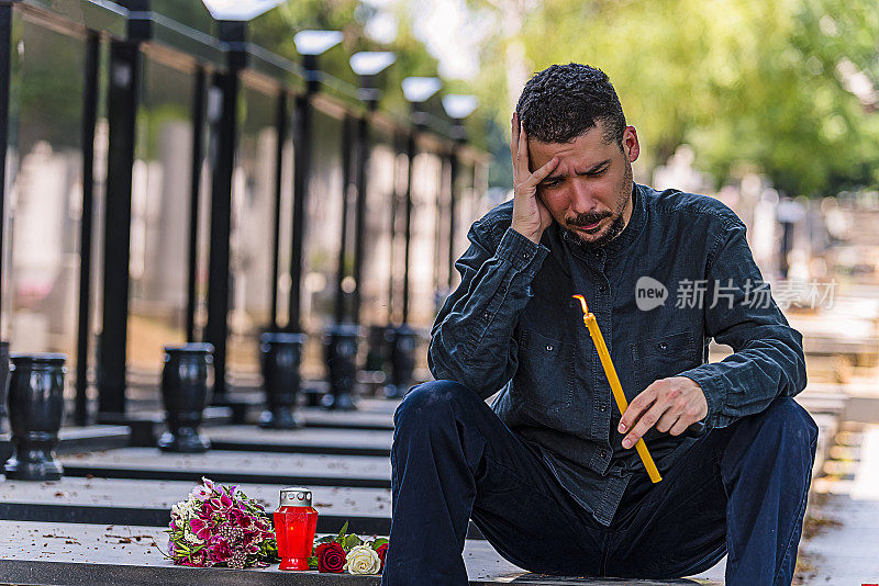 在墓地上拿着蜡烛的情绪紧张的男人