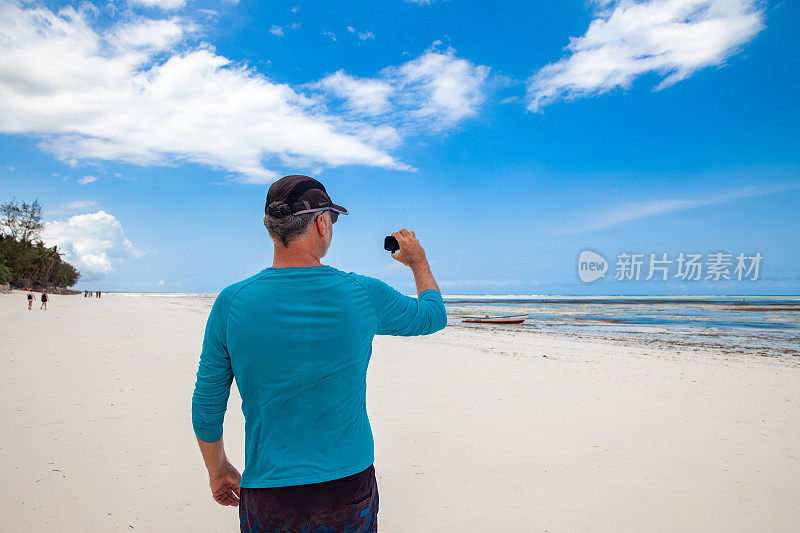 成年男子用小型可穿戴相机拍摄夏日海岸线