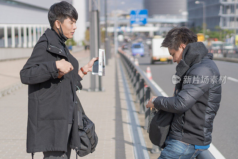 年轻的亚洲男子和日本朋友寻找旅游地点使用手机和花时间在亚洲旅行