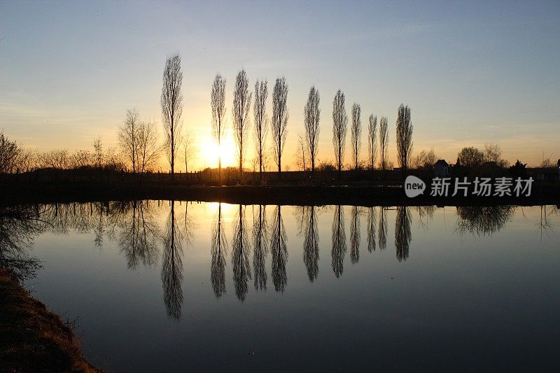 夕阳西下，树木倒映在湖面上