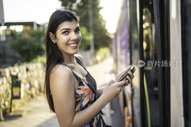 一名年轻女子乘公交车，用手机看镜头的肖像