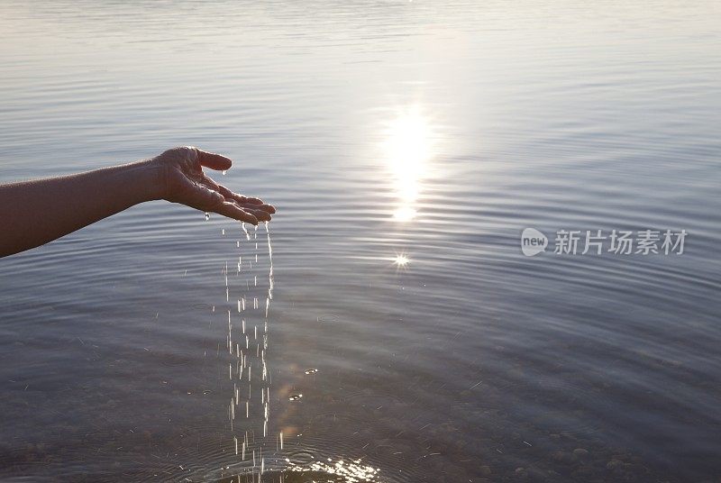 用手从阳光下的湖里舀水