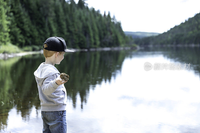 小红发男孩在夏天往湖里扔石头