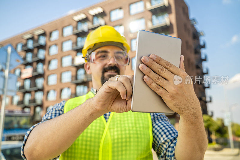 工程师、建筑工人或建筑师在新建小区前手持数码板