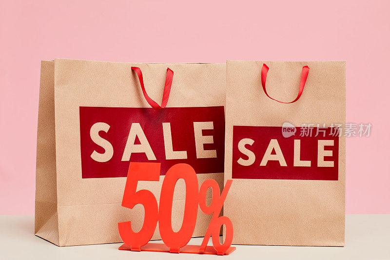 特写购物袋与销售字母和50%平板电脑的商店展示窗口