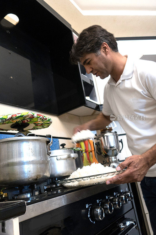 成熟的男人在家庭厨房烹饪传统的伊朗饭，米饭和蔬菜