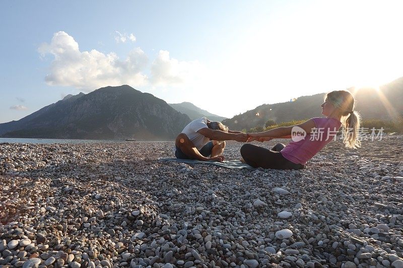 父亲和女儿在海滩上练习日出瑜伽