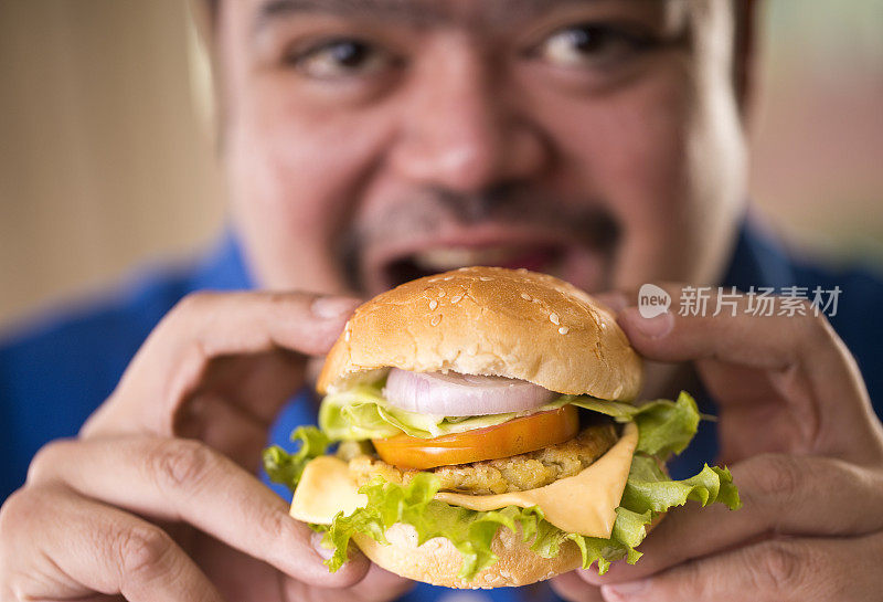 一个正在吃快餐汉堡的男人