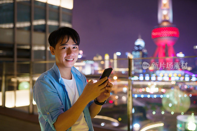 年轻的亚洲男子在晚上使用智能手机