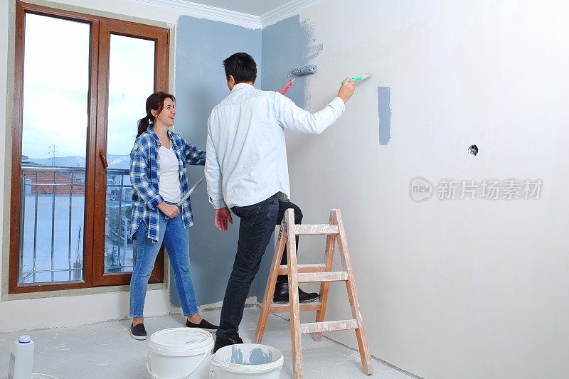 一对年轻夫妇正在粉刷他们新公寓的内墙