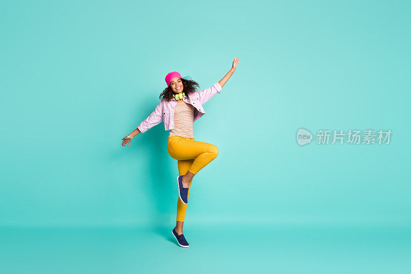 丰满的身体尺寸转身的照片开朗积极可爱漂亮的女朋友跳舞在黄色裤子条纹t恤帽子头饰夹克感觉自由孤立生动的颜色蓝绿色背景